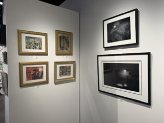 An art gallery wall displaying a collection of framed artworks, including four smaller pieces in gold frames and two larger pieces in black frames.